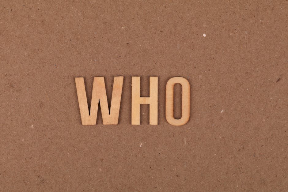 Wooden letters forming the word WHO on a textured cardboard surface.