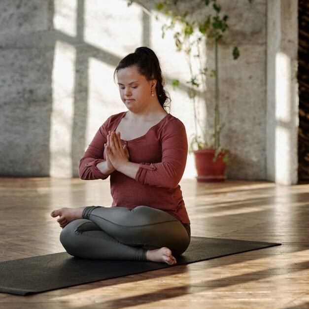Woman practicing yoga on a mat indoors, finding inner peace and relaxation in a serene setting.