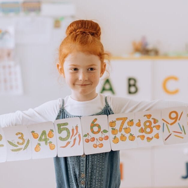 Young girl showcasing number cards in a vibrant classroom setting.